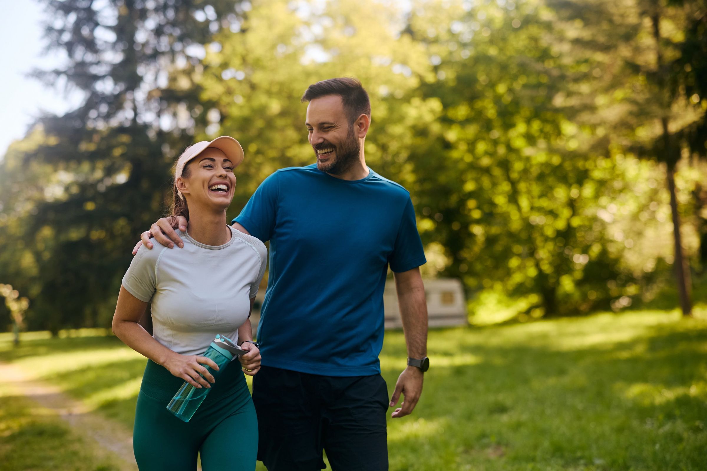 Two people laughing together on a walk through a sunny park
